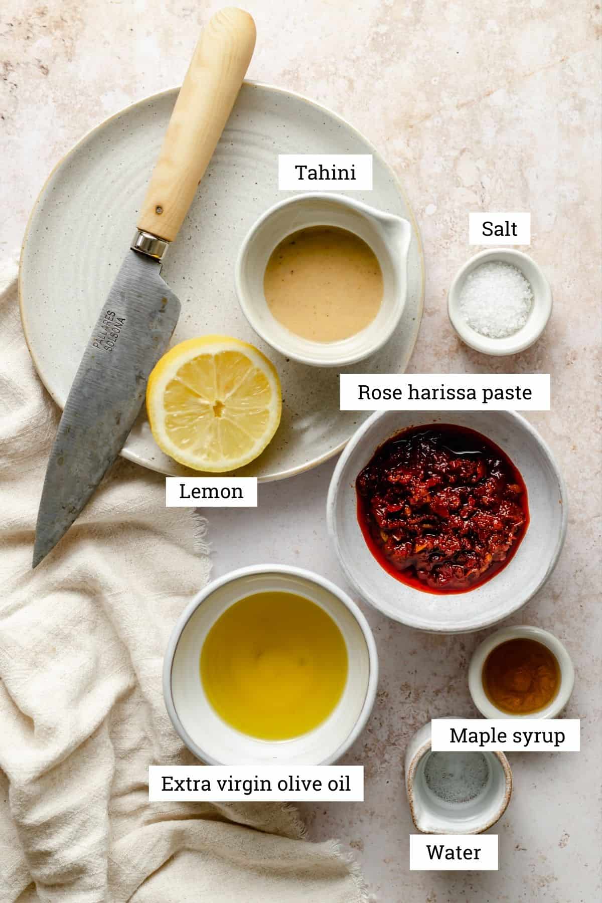Ingredients for harissa dressing including, tahini, rose harissa paste, oil, maple syrup, lemon and salt.