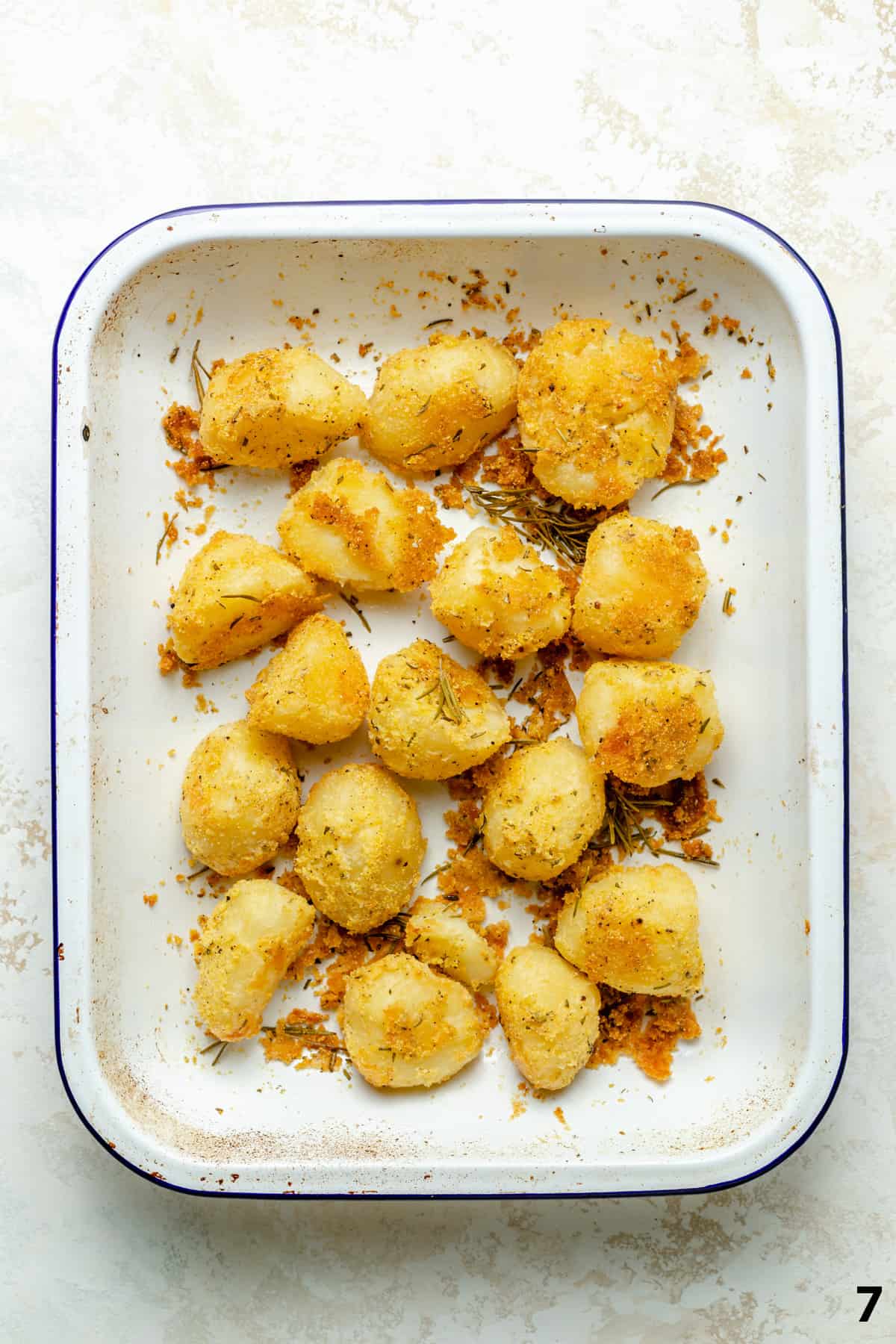 Final process of crispy roasted potatoes in a roasting pan with crispy bits all around.