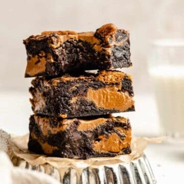 A stack of biscoff brownies on a tart tin with the top one bitten into.