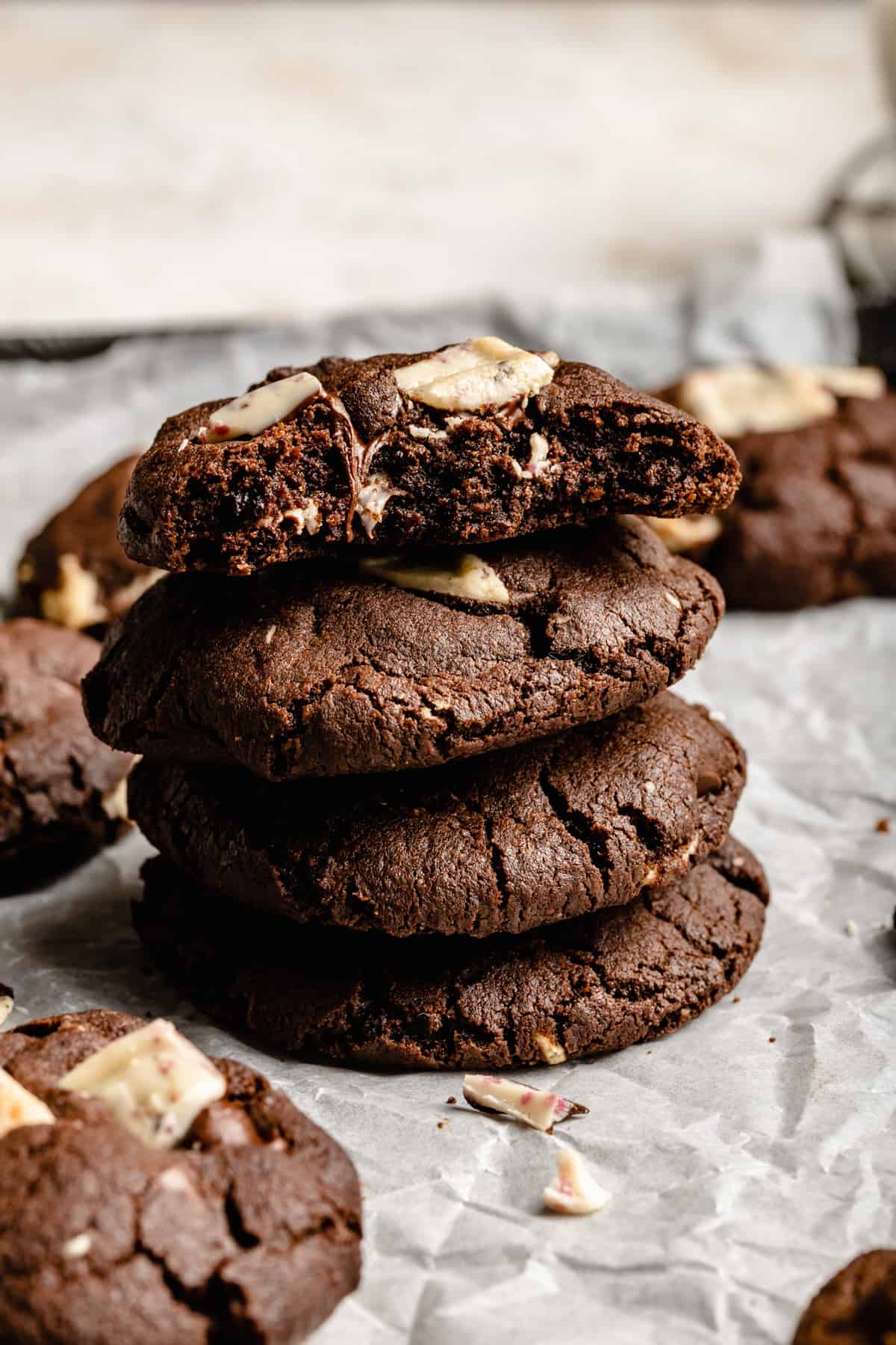 A stack of mint chocolate chip cookies with one on top broken open showing the insides with gooey chocolate.