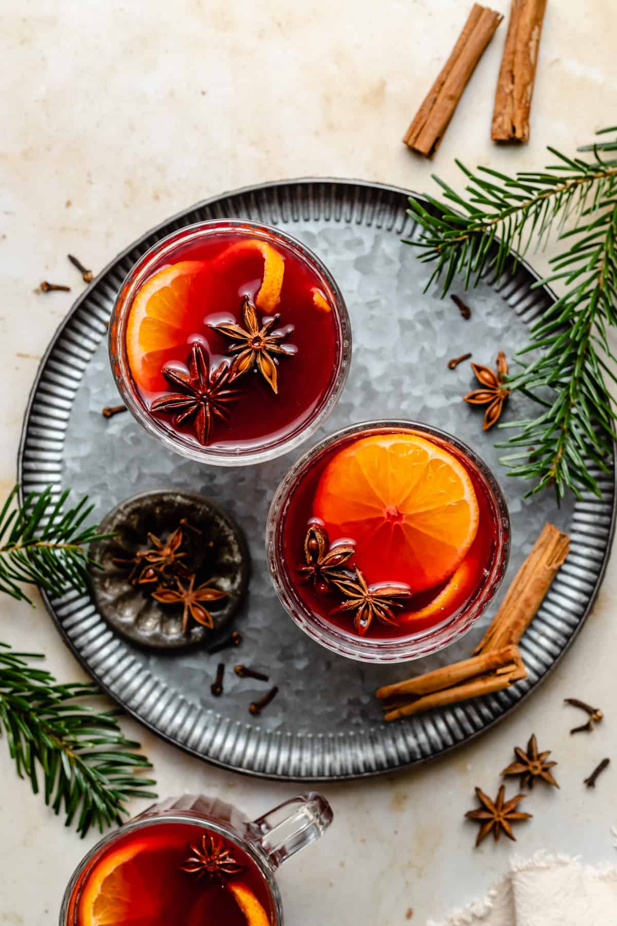 Two glasses of mulled wine on a tin tray with fir tree and whole spices around by. 