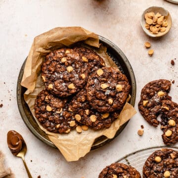 Nutella Oatmeal Peanut Butter Chip Cookies in a parchment lined baking tin with extra cookies around.