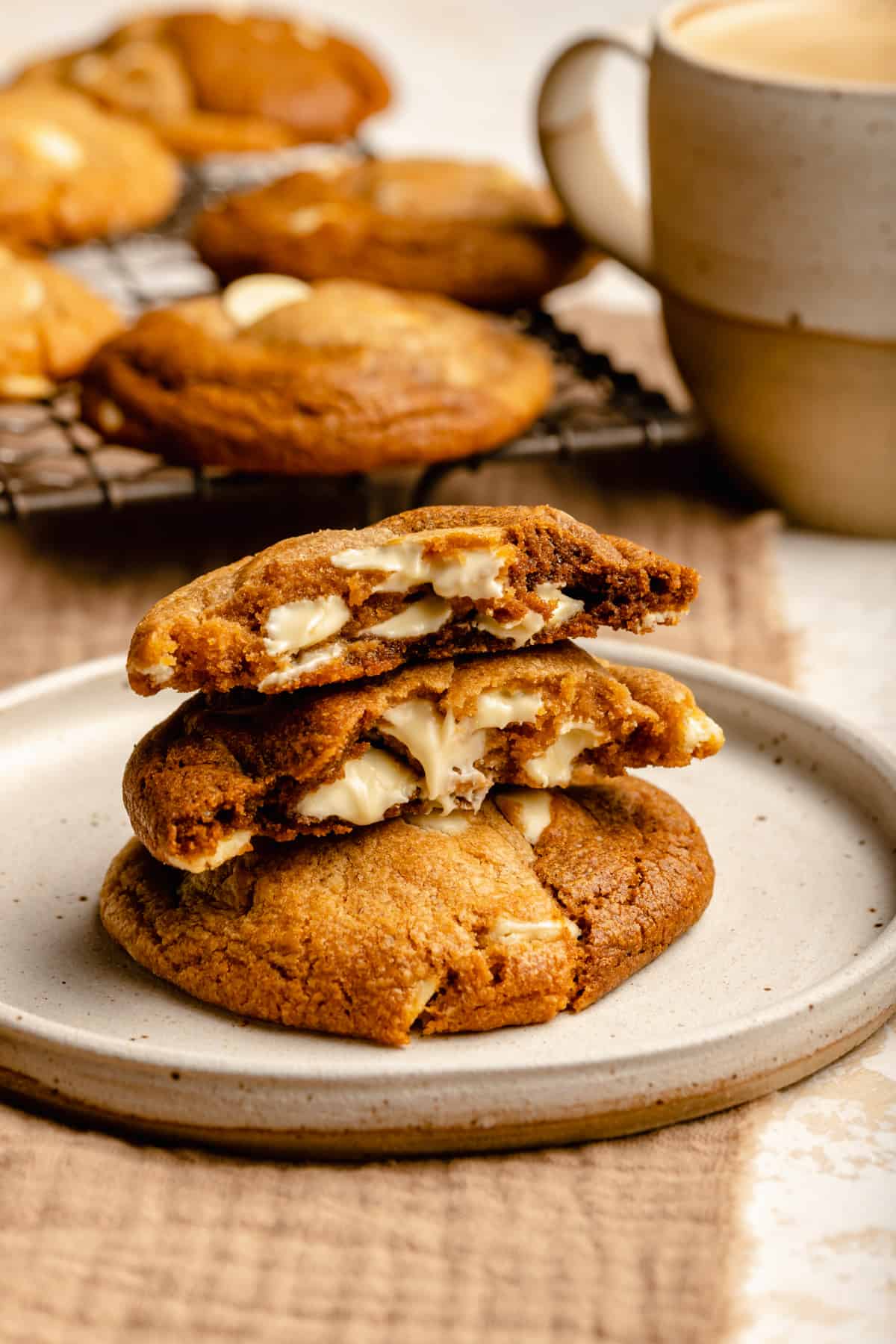 A gingerbread swirl cookie broken in half on top of another cookies on a plate showing the chewy insides and molten chocolate buttons.
