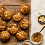 White chocolate gingerbread swirl cookies on a cooling rack with a bowl of chocolate buttons next to it.