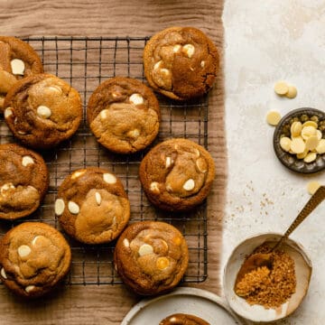 White chocolate gingerbread swirl cookies on a cooling rack with a bowl of chocolate buttons next to it.