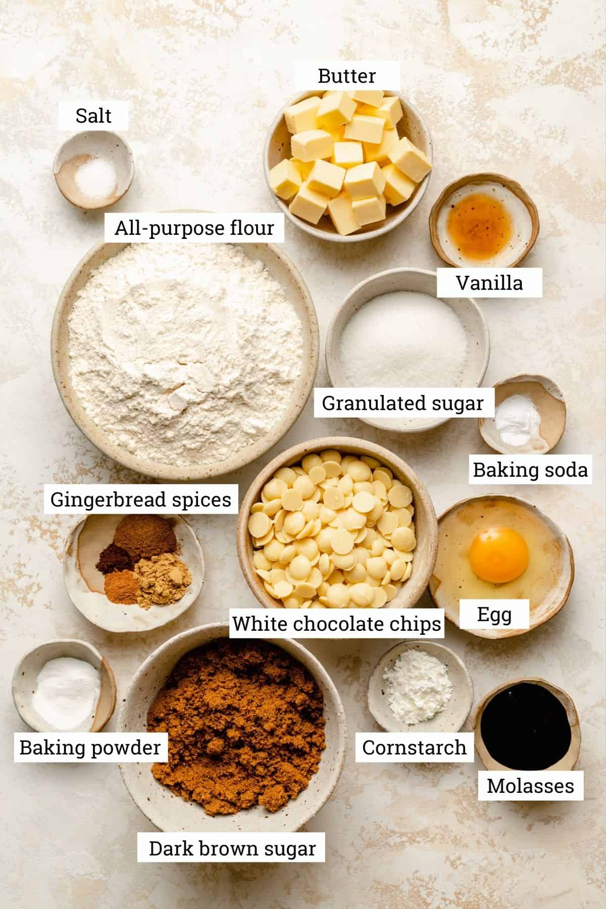 An array of bowls of ingredients to make gingerbread swirl cookies including, sugar, flour, chocolate buttons and spices.