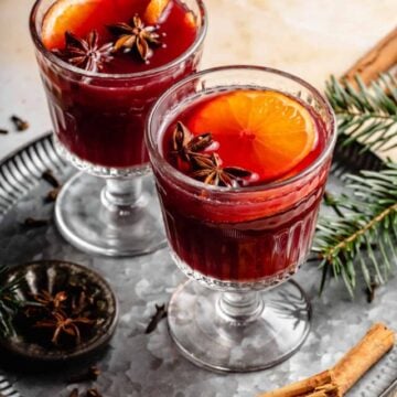 Non alcoholic mulled wine served in glasses on a plate with spices around.
