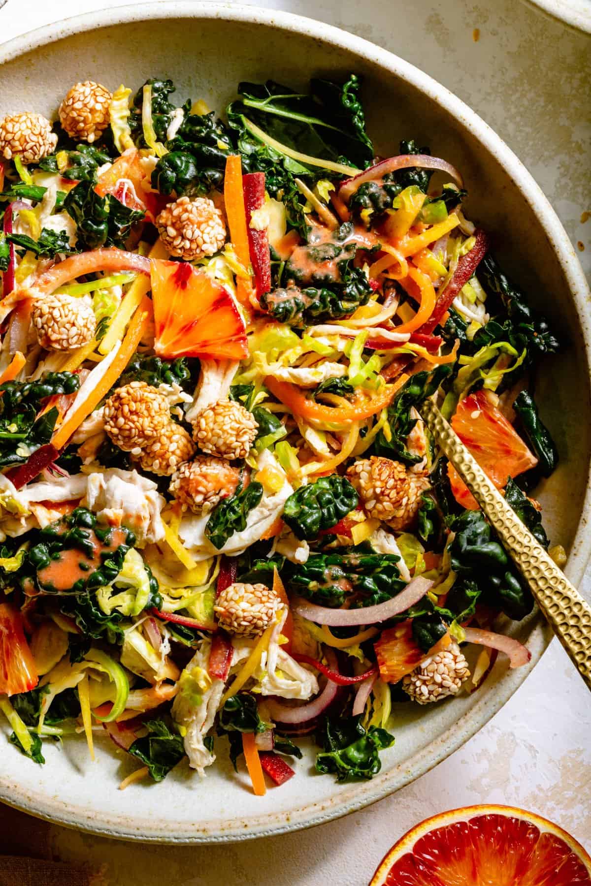 A close up showing the citrus salad with dressing drizzled on top with crispy sesame chickpeas and a fork.