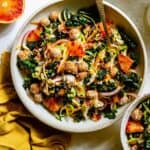 Kale citrus salad served in a bowl with blood orange nearby and a fork.