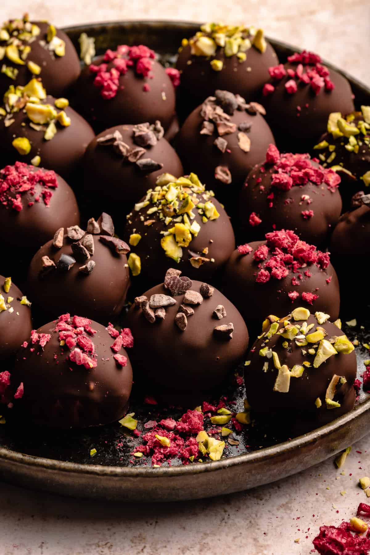 Plate of raspberry dark chocolate truffles, with various toppings on.