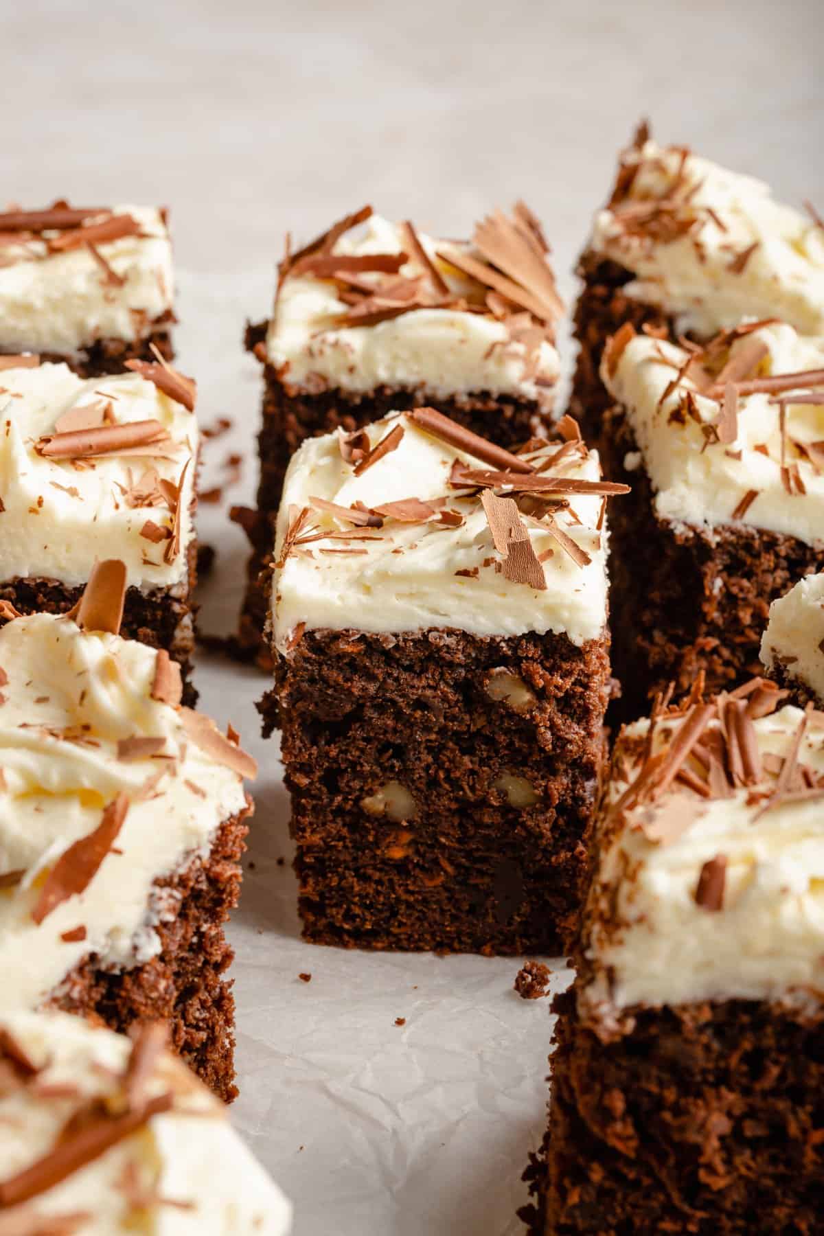 Chocolate carrot cake cut into squares with cream cheese frosting showing the texture of the sponge. 