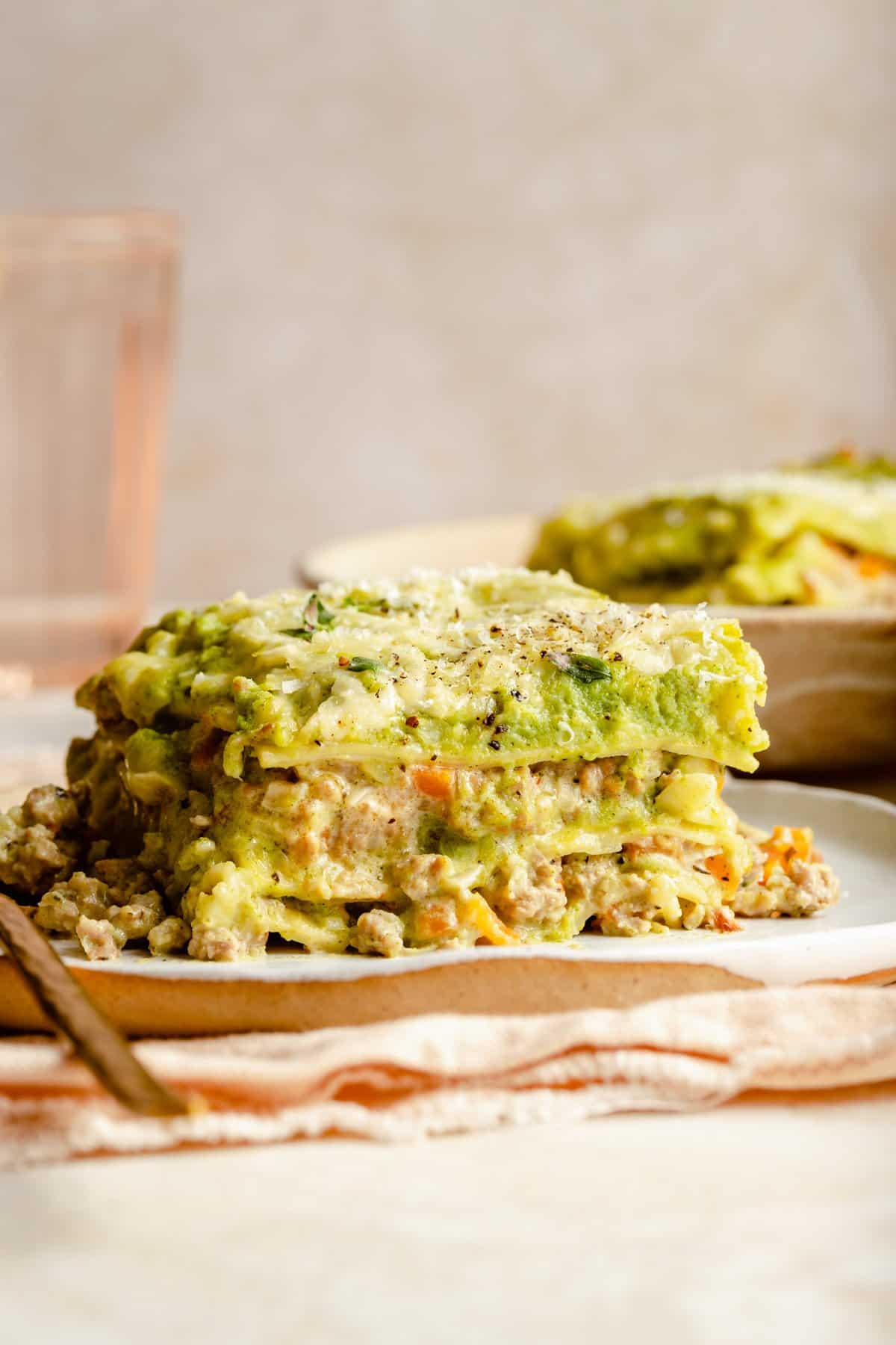 Portions of broccoli chicken lasagna served on plates showing the broccoli and chicken layers. 