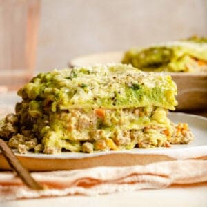 Broccoli chicken lasagna slice on a plate showing all the layers with a fork to the side.