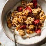 Peanut butter granola in a bowl with yoghurt and a spoon.