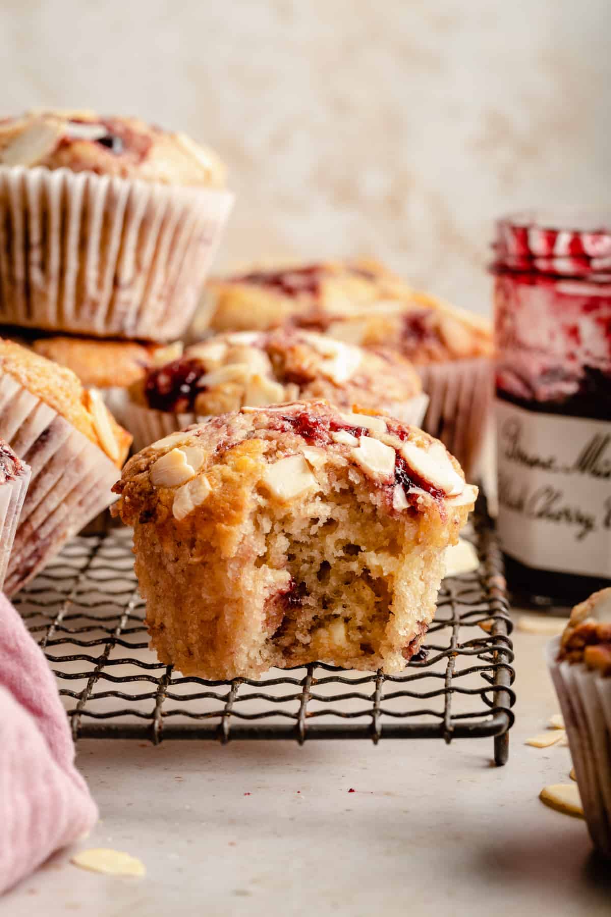 Cherry sourdough muffin on a wire rack with a bite taken out of it showing the inside.