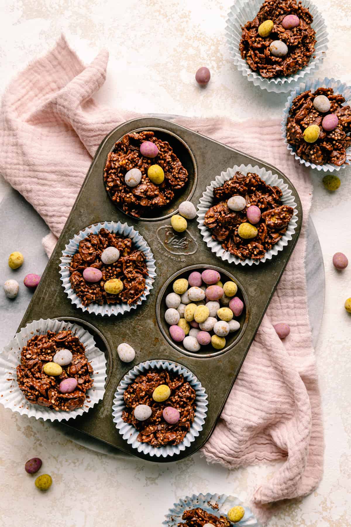 Chocolate cornflake cakes in cases on a baking tin with mini chocolate eggs around.