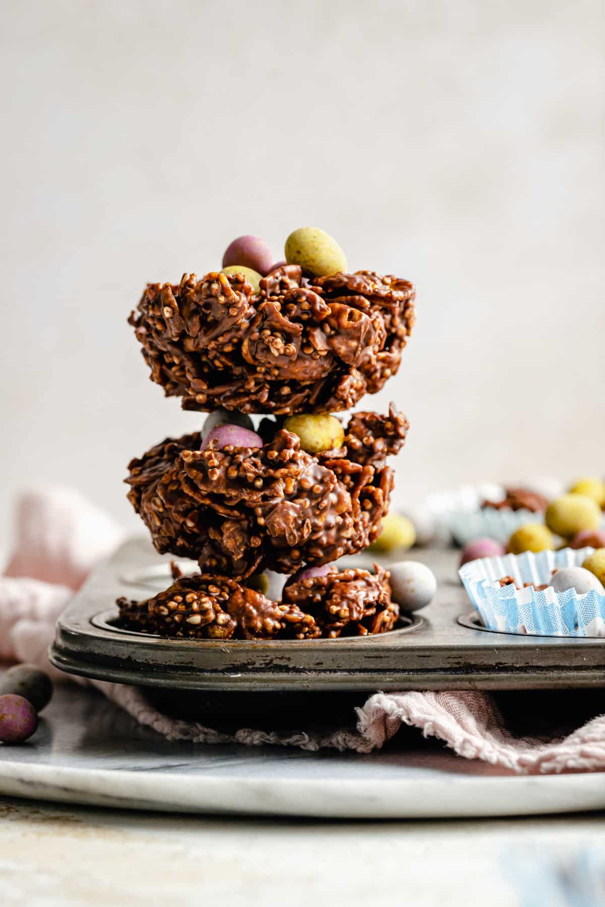 Chocolate cornflake cakes stacked in a baking tin showing the texture and mini eggs on top.