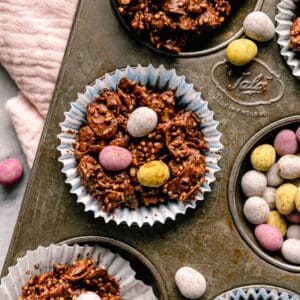 Chocolate cornflake cakes in a baking tin with mini chocolate eggs on top and around with a pink napkin.