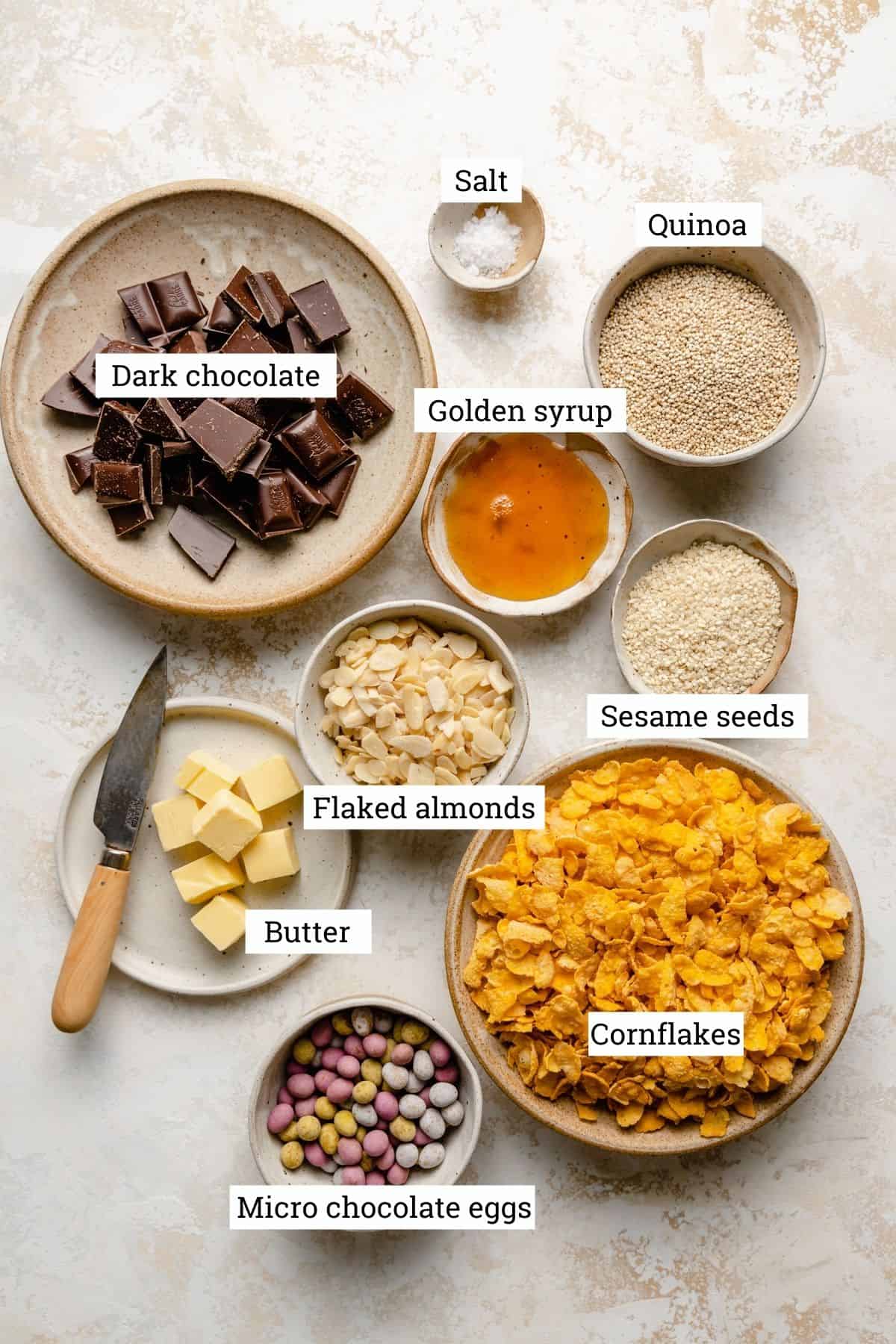 ingredients in various bowls for chocolate cornflake cakes on a plaster background.