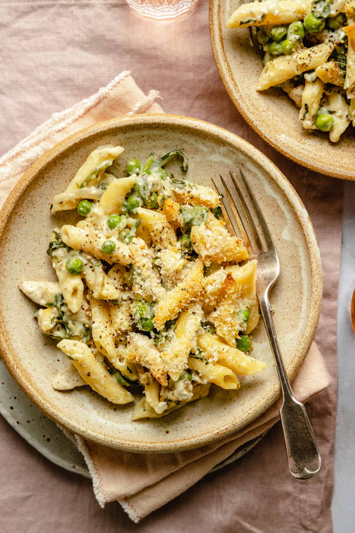 Creamy chicken pasta bake served in a bowl with a napkin and a fork.