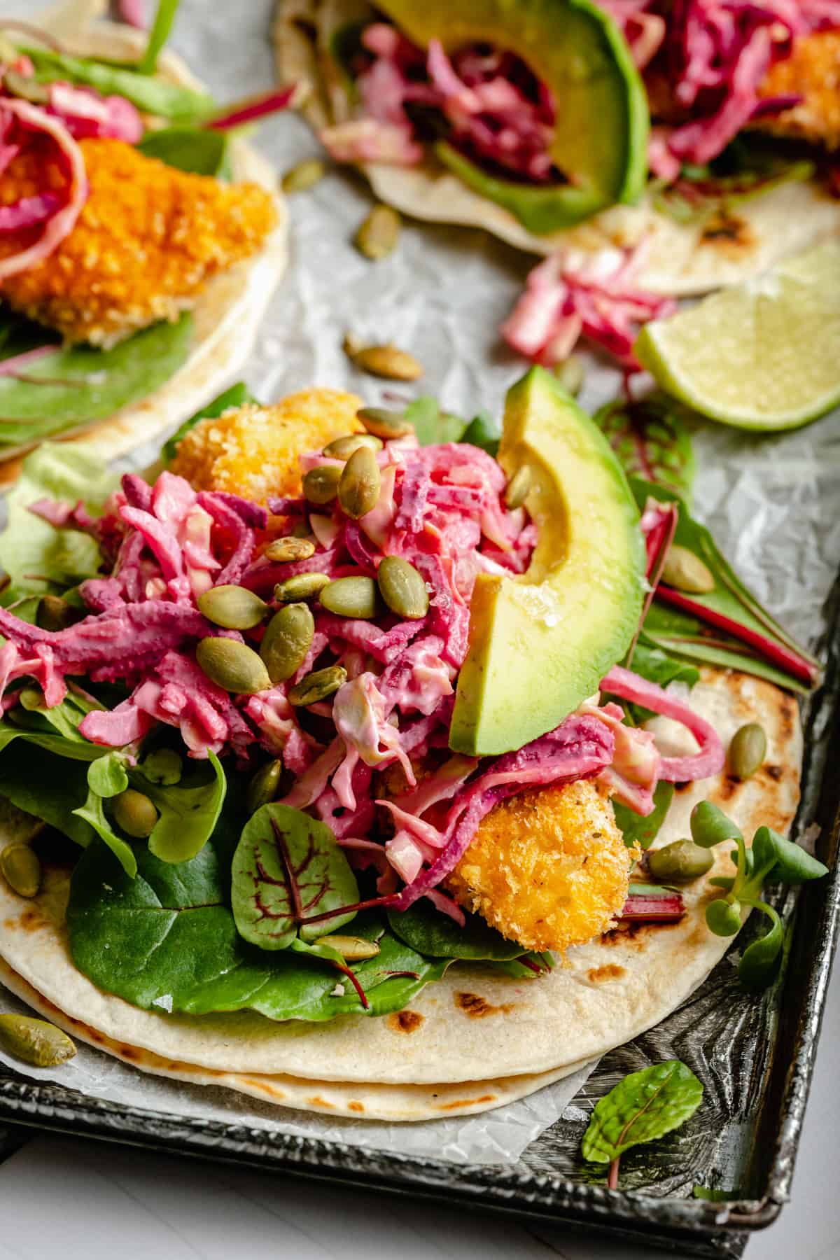 A close up showing the crispy chicken in a taco with beetroot slaw on top.