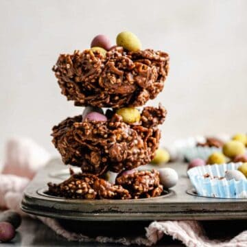 Chocolate cornflake cakes stacked on top of each other on a plate with mini eggs decorating for Easter.