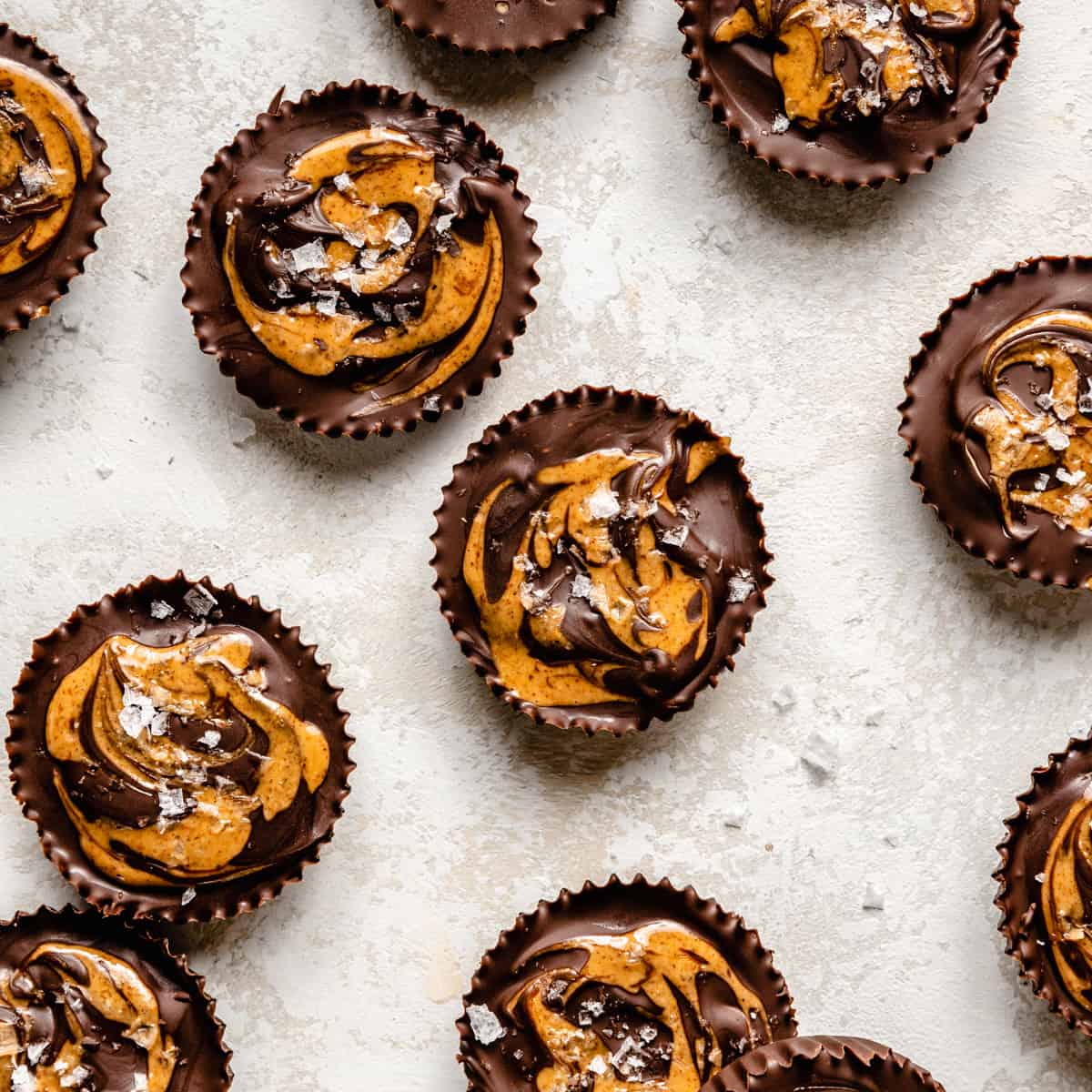 An array of almond butter cups with almond butter swirl and flaky salt on top. 