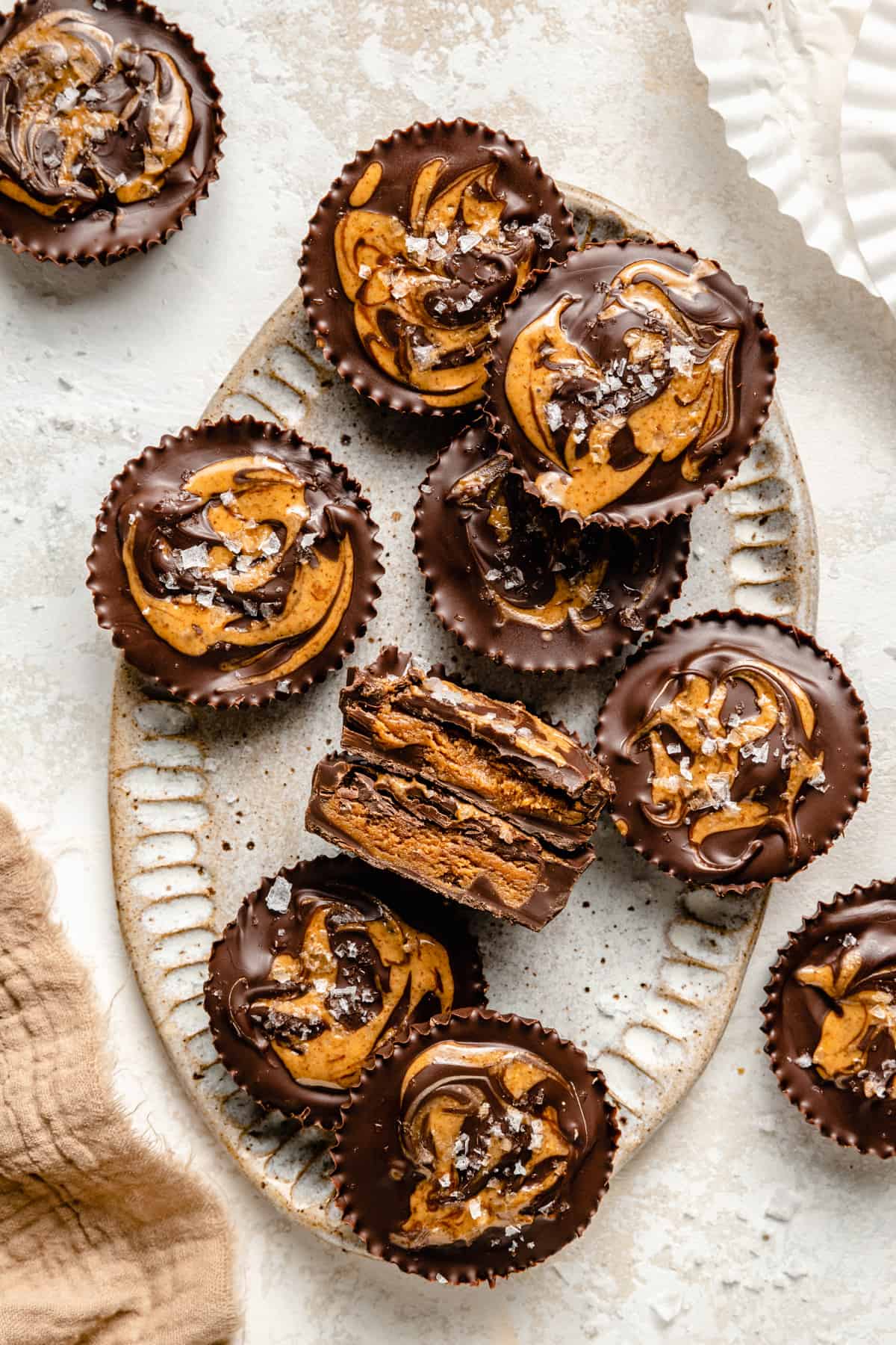 Almond butter cups on a platter with one cut open showing the inside with a napkin.