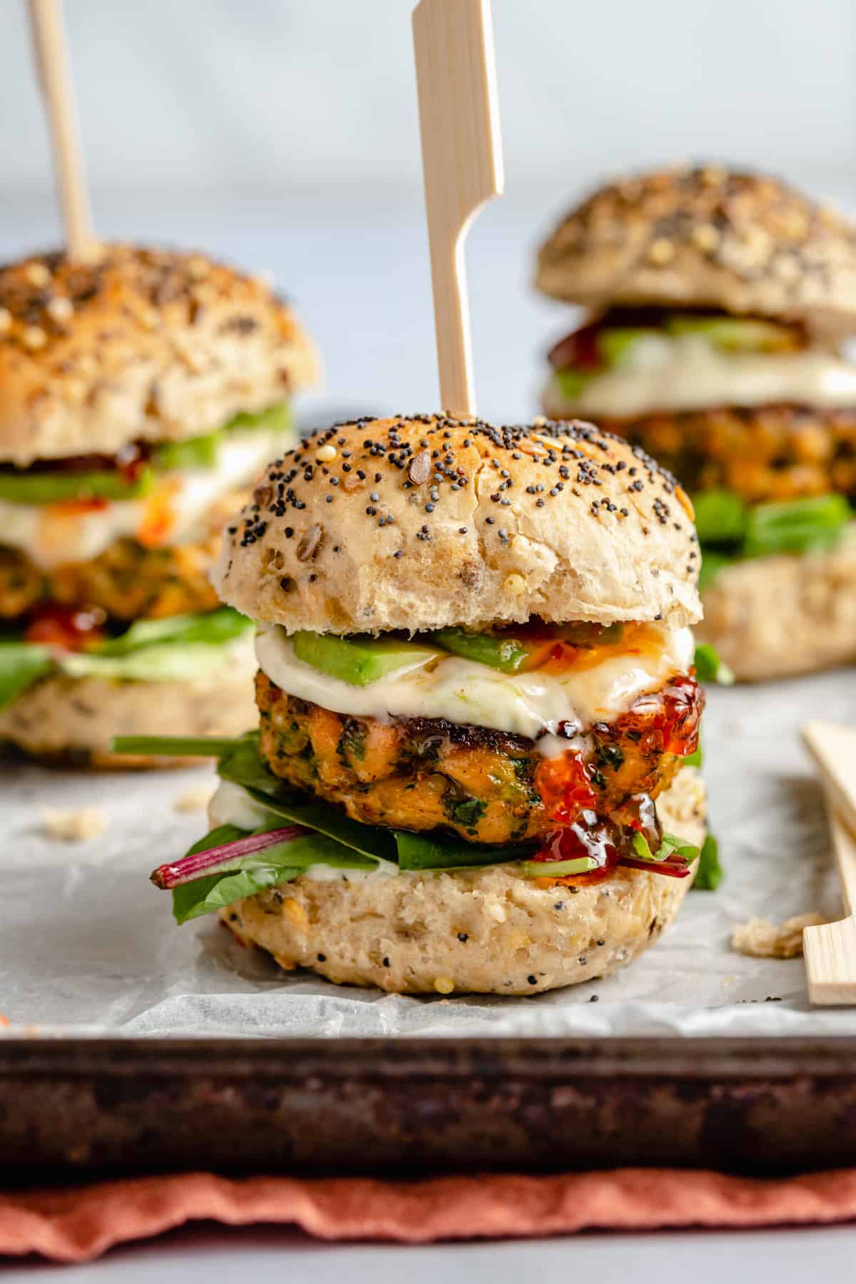 close up of salmon slider on parchment lined baking sheet with lime mayo and chilli jam.