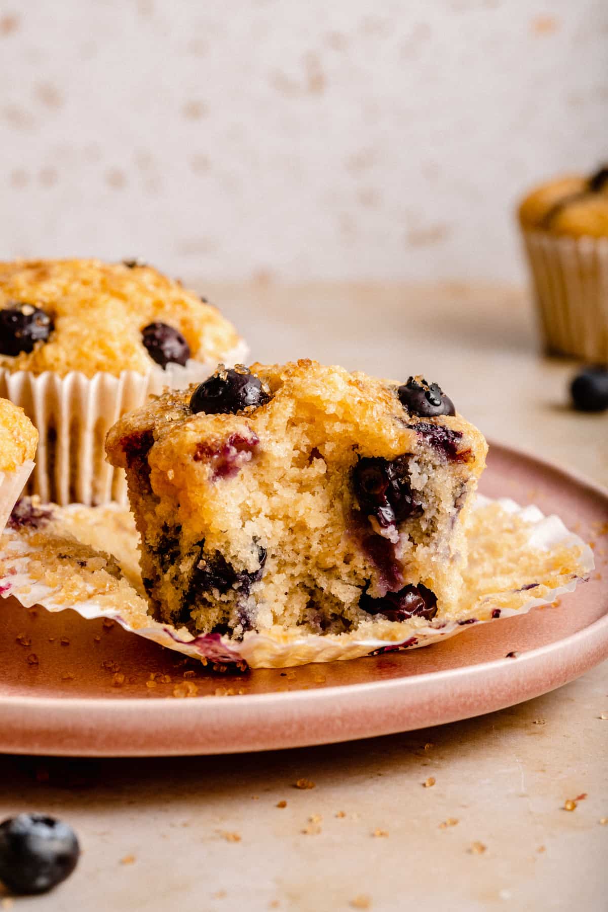 A blueberry muffin with a bite taken out on a plate showing the inside.