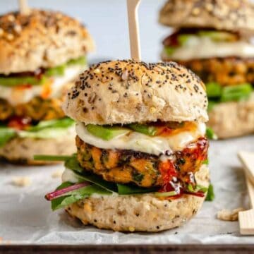 Blackened salmon sliders on a lined baking sheet with a skewer in the top.