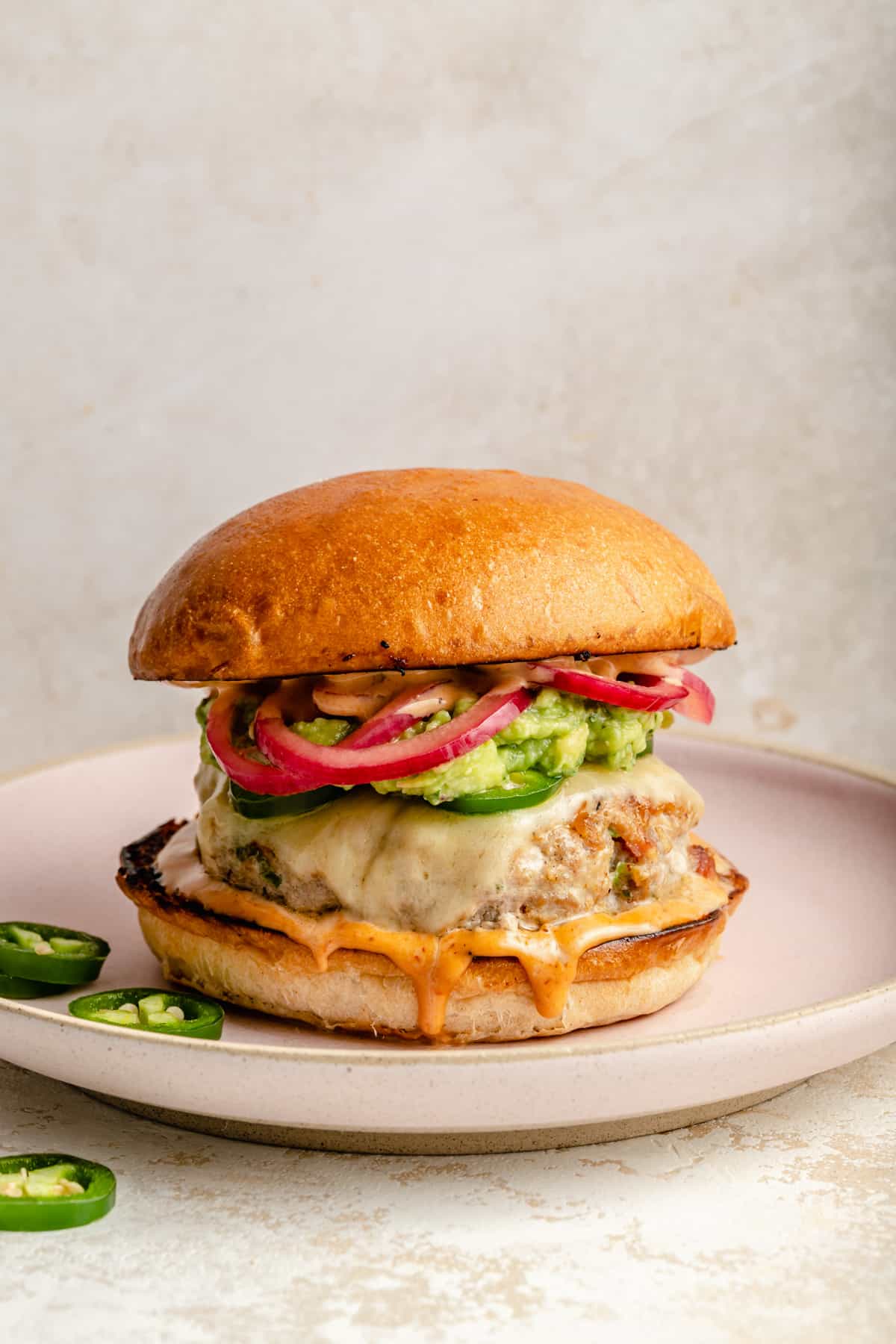 Turkey burger assembled on a plate with extra jalapeno slices around.