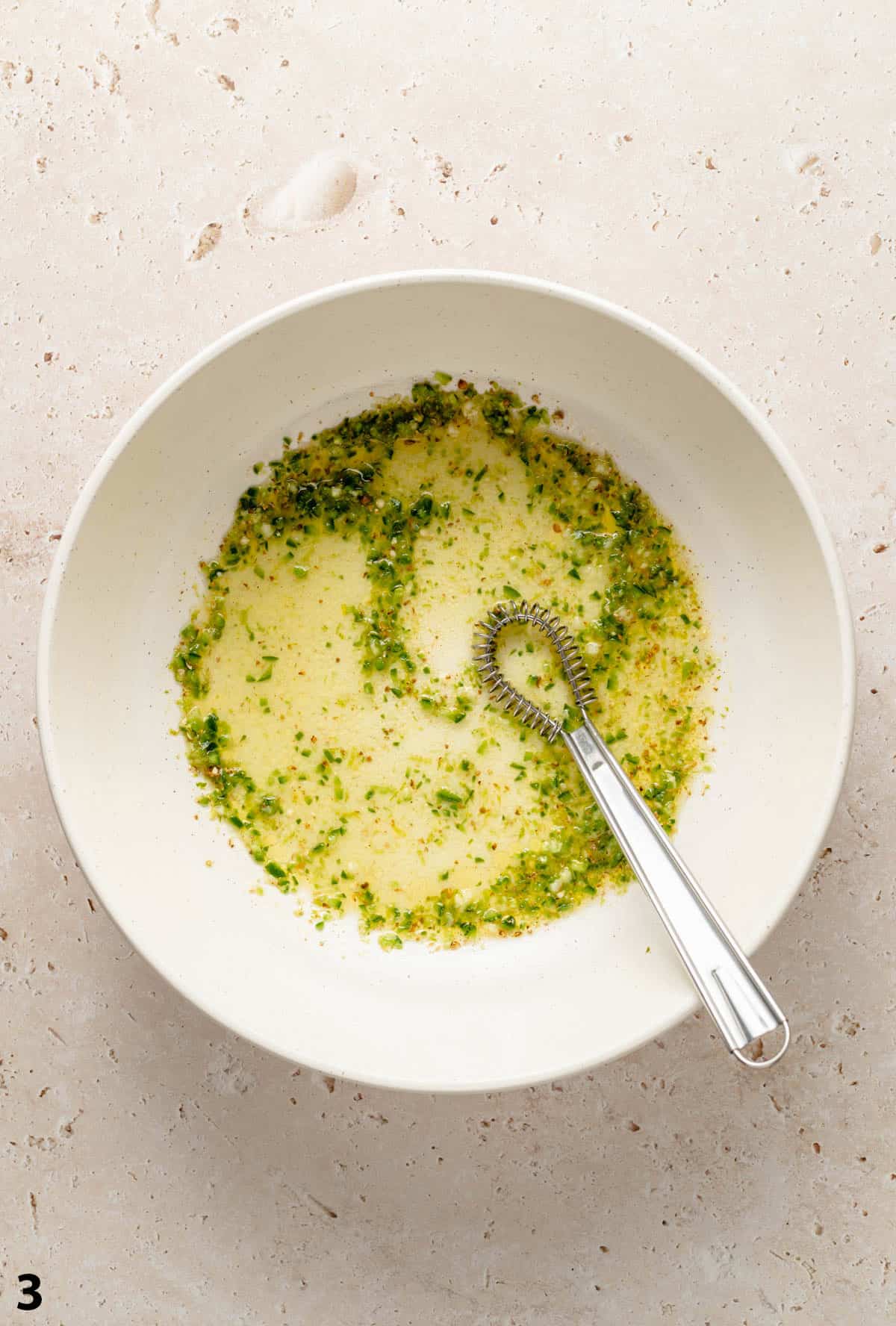 Jalapeno lime dressing whisked together in a large bowl with a whisk.