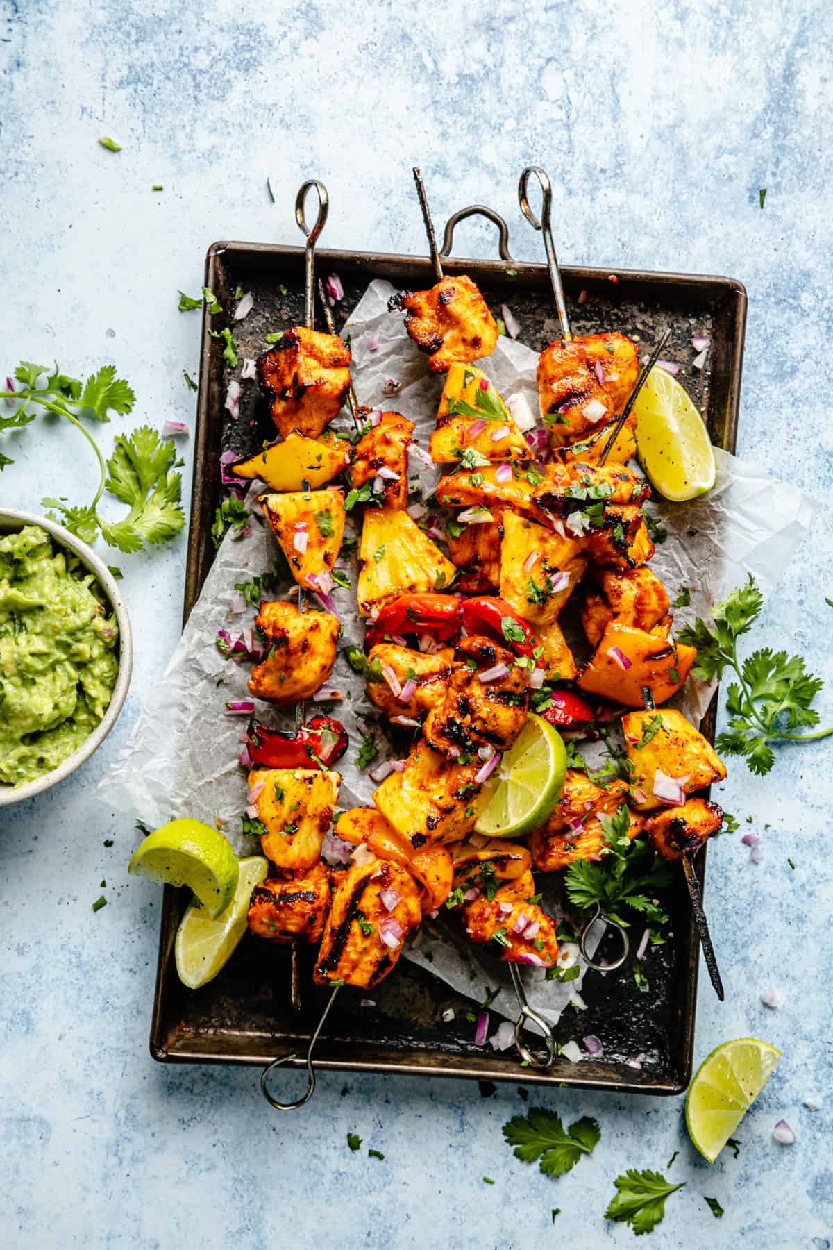 Pineapple chicken kabobs grilled and served on a baking sheet on parchment.