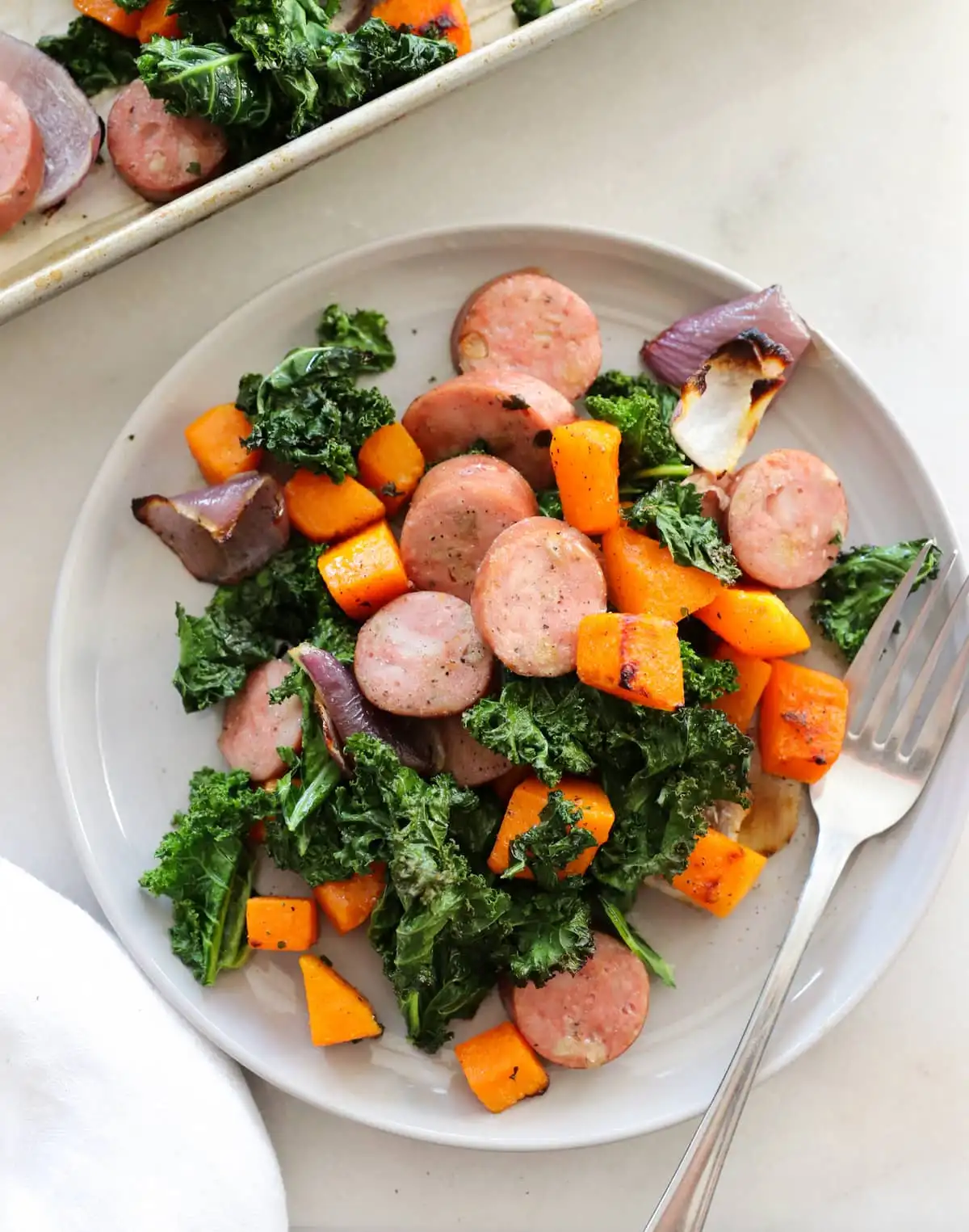 Healthy Sheet Pan Chicken sausage served on a plate with a fork.