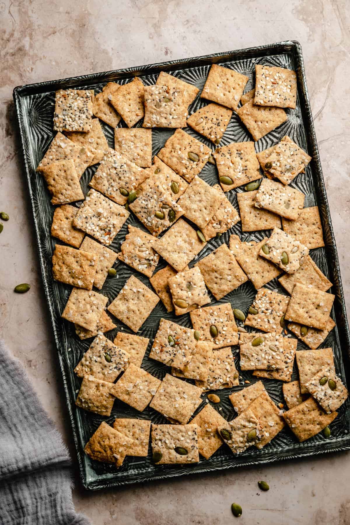 A metal tray with sourdough crackers spread out over it with a napkin to the side.