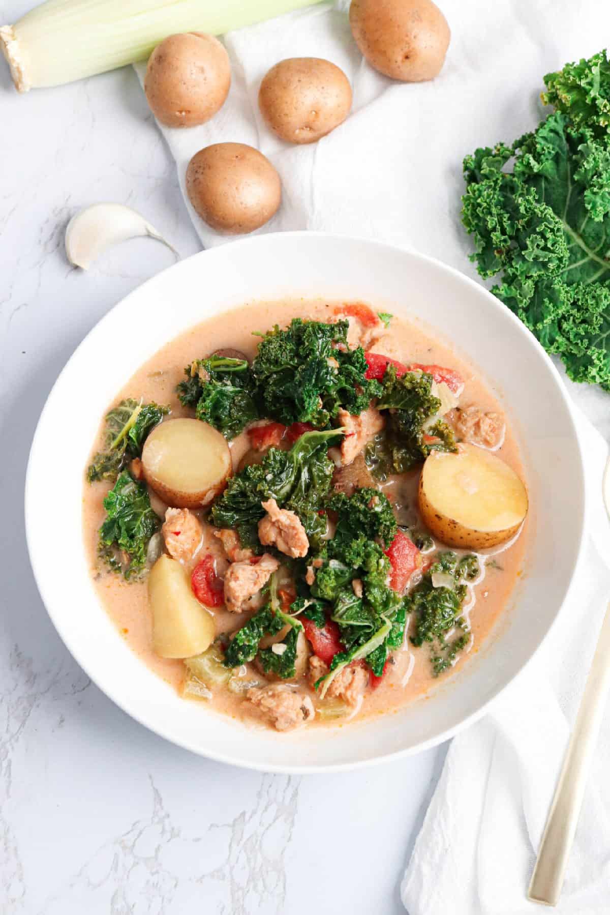 Creamy Sausage Potato soup in a bowl with a spoon to the side.