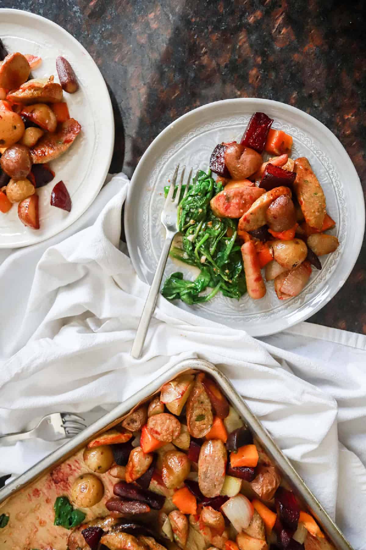 Sheet pan sausage and veggies served up on two plates.