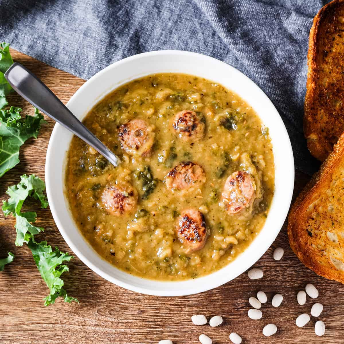 White bean chicken sausage and kale soup in a bowl with a spoon.