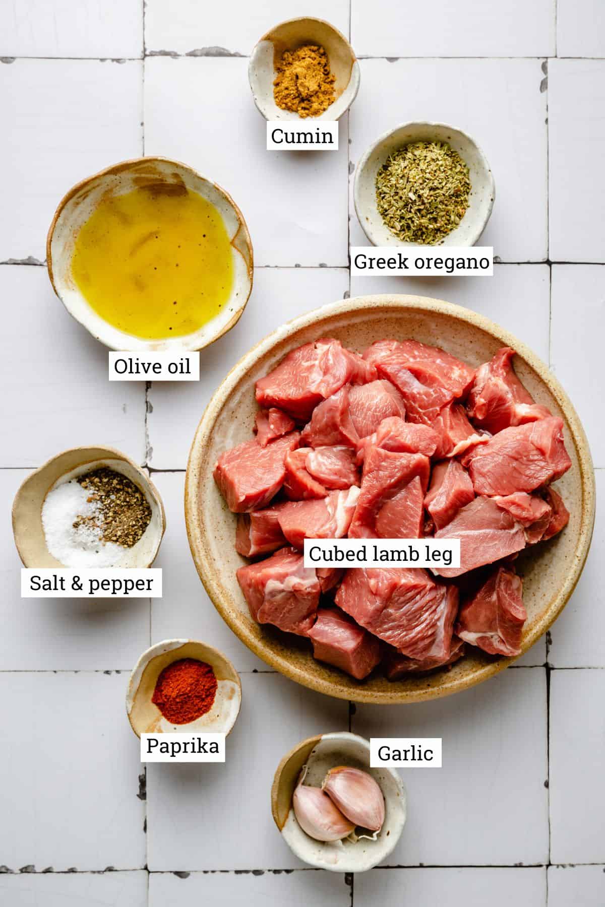 Ingredients for lamb souvlaki in bowls with labels.
