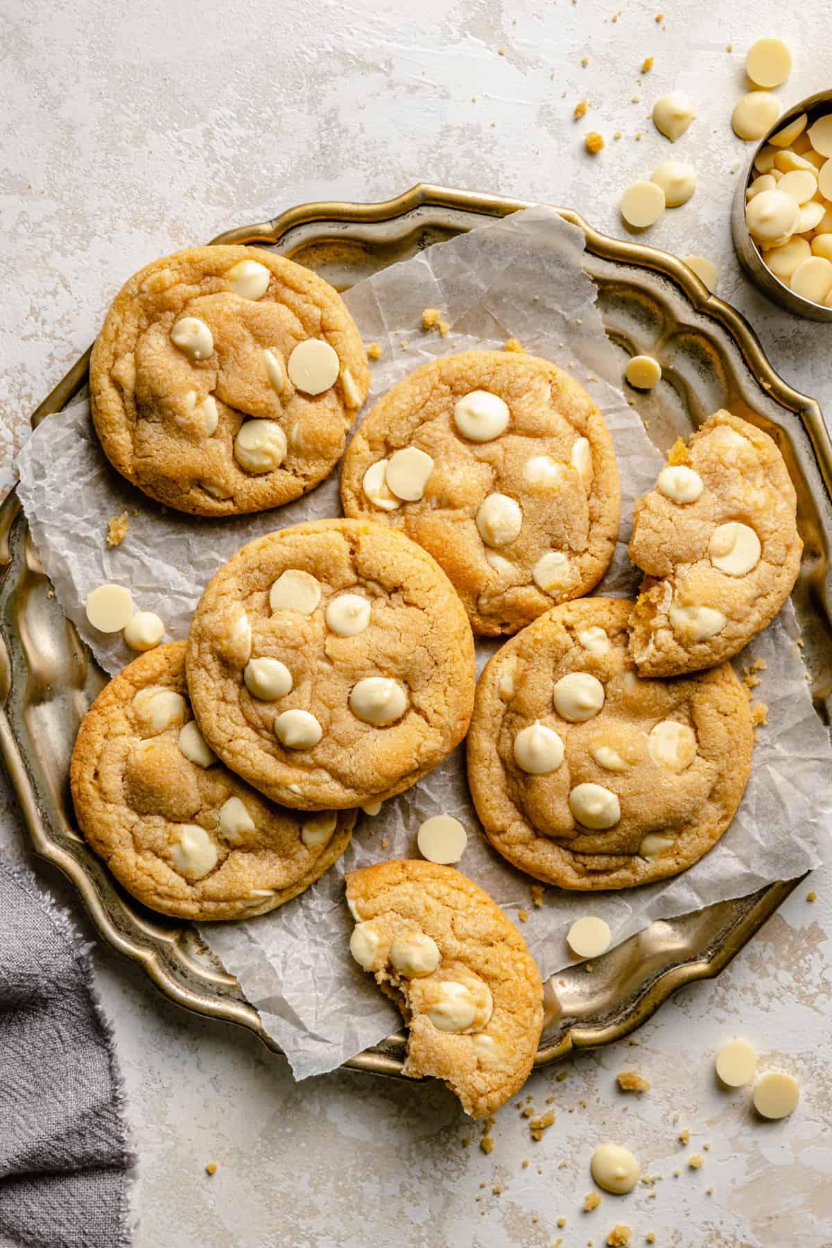 A golden platter lined with parchment with lemon white chocolate cookies on it.