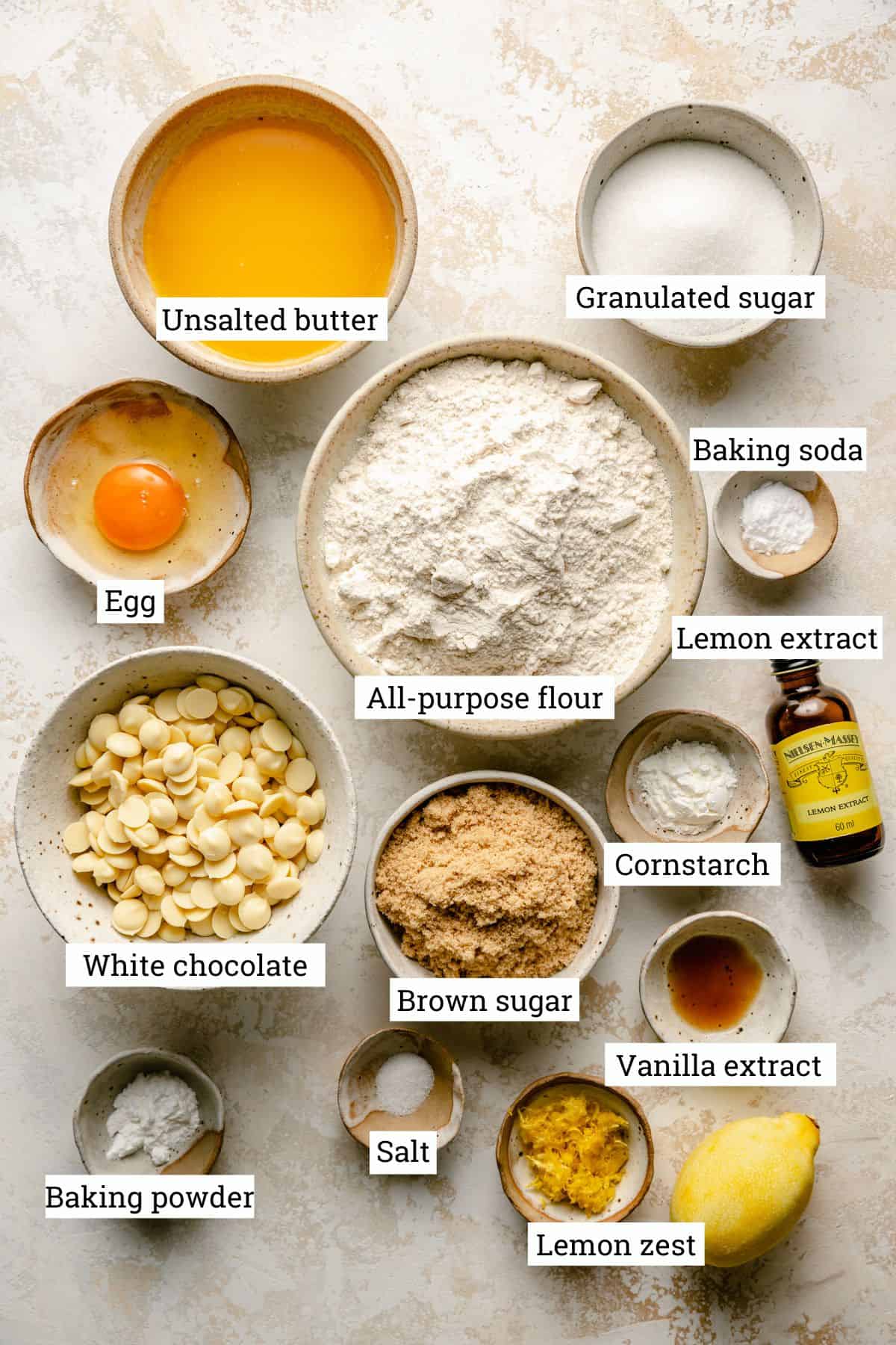 Ingredients for lemon white chocolate cookies in various bowls with labels.