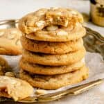 Chewy lemon white chocolate cookies in a stack with one taken a bite out of on top.