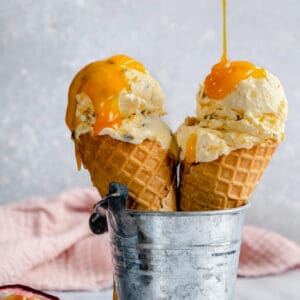 Passion fruit ice cream scooped into waffle cones with passion fruit curd drizzled on top.