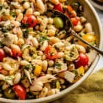 Cannellini bean salad served in a bowl with a spoon and napkin to the side.