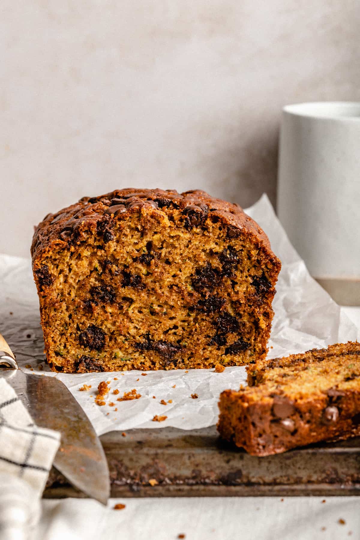 A cross section of the zucchini bread on a metal tray with parchment paper and a knife.