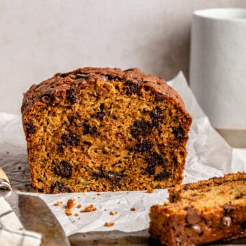 chocolate chip zucchini bread cut open on a baking sheet with a knife.