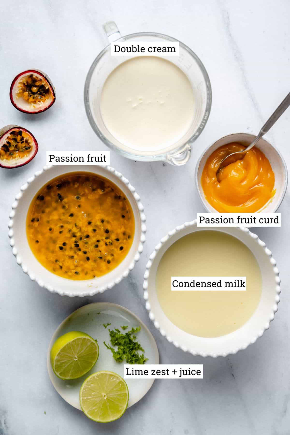 Ingredients for ice cream in various bowls on a marble background.