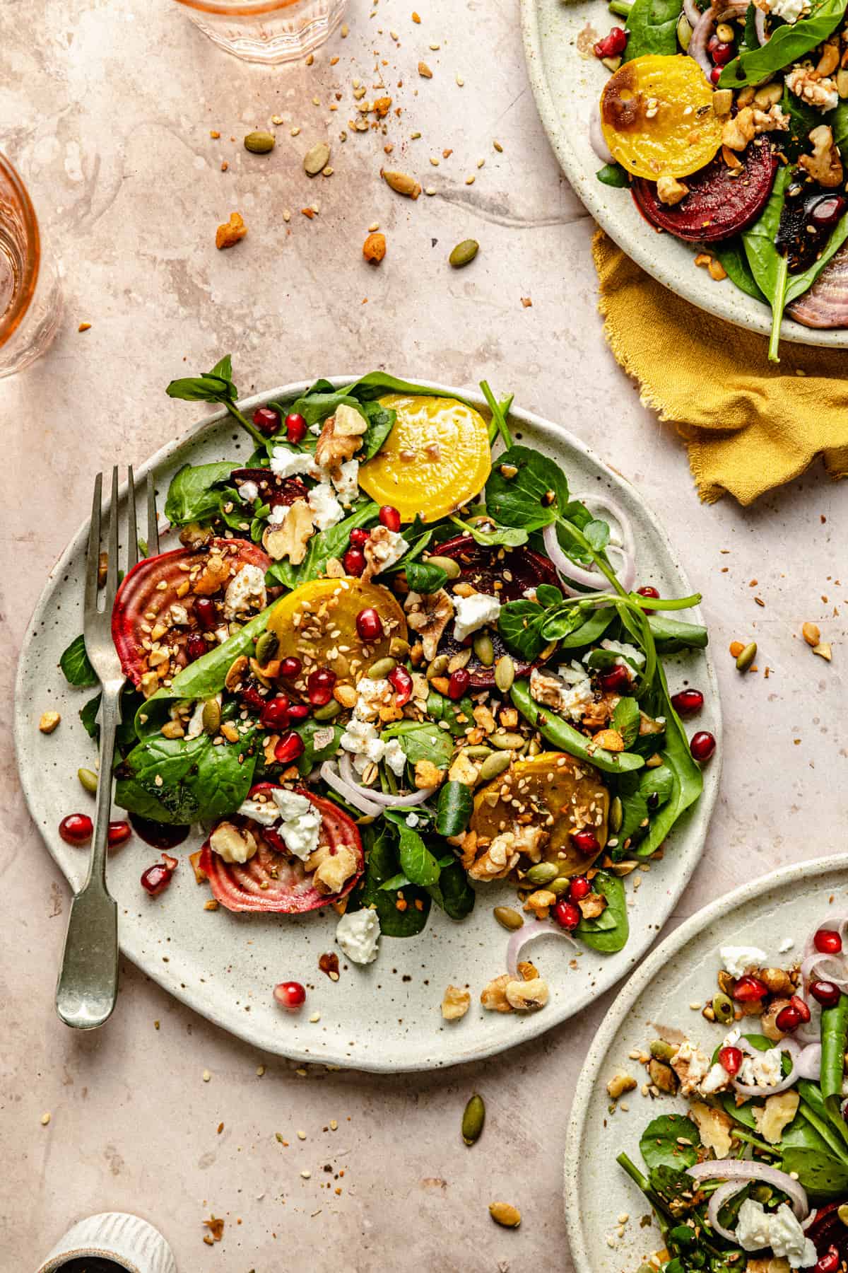 Three plates of beetroot feta walnut salad dressed and topped with dukkah.