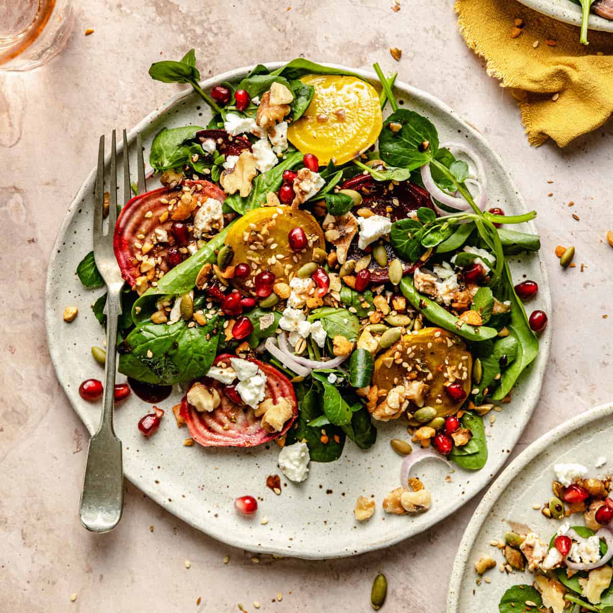 A plate of beetroot feta walnut salad with dukkah on top, fork to the side and a napkin.